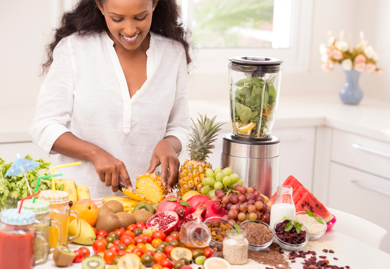 Happy woman preparing healthy fruit shakes, using mixer grinder.